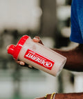 Athlete holding an Enervit Sport shaker with a protein shake after training