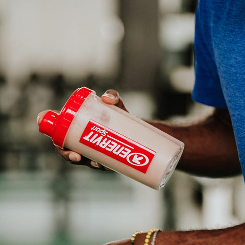 Athlete holding an Enervit Sport shaker with a protein shake after training